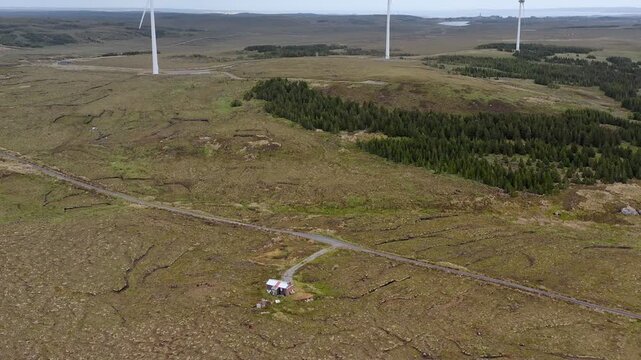 Descending drone shot from three wind turbines to a roadside shieling on Lewis.