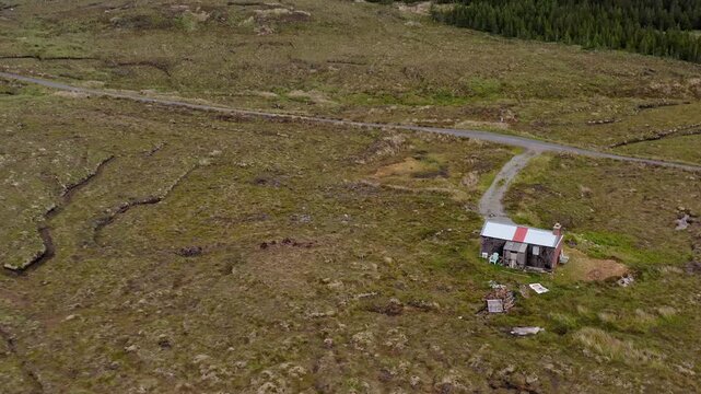 Drone shot tilting from a moorland shieling to a wind farm on the Hebrides.
