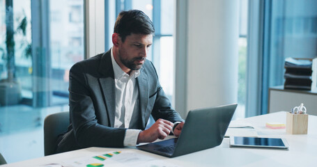 Fototapeta premium Man, accounting and typing with laptop at office for review, charts and documents at company. Person, computer and stats with bookkeeping, administration and revenue graphs at financial agency