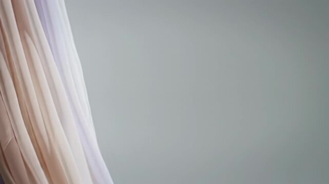 Wide video of sheer silk chiffon fabric in pale peach, light lavender, and off-white, billowing gracefully in soft, diffused light with luminous negative space. Luxurious tranquility concept