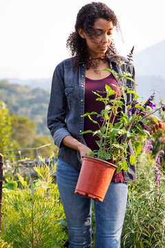 Woman holding plant in her home garden