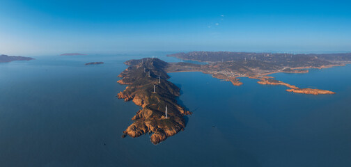 Naklejka premium Aerial panorama of wind turbines on a rocky coastline peninsula.