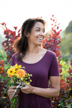 Woman holding basket of fresh cut garden flowers in garden