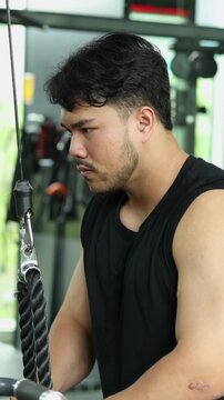 Vertical Close-Up of Man Performing Tricep Rope Pushdowns in Gym