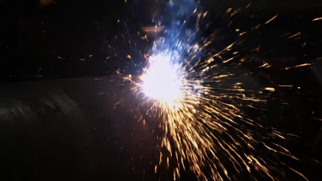 Sparks flying in all directions with bright white and blue flame on dark background welding explosion