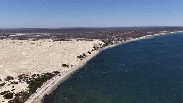 4K aerial drone view of Great Australian Bight coastline, jetty, caravan park, turquoise ocean, sand dunes, white sand beach and limestone cliffs (Fowlers Bay, South Australia)