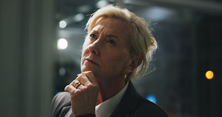 Night, thinking and mature woman in office with project, business plan and brainstorming at digital...