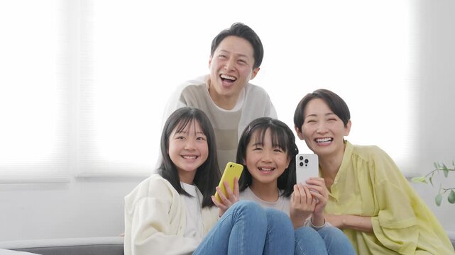 笑顔でスマホを持つ小学生の女の子の家族