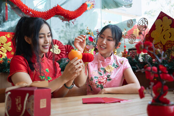 Two Asian women in traditional Cheongsam celebrating Chinese New Year with festive activities © Oil And Den