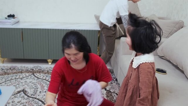 A caring mother helps her young daughter put on tights while child giggles and plays. Warm family moment full of affection, humor, and everyday routine in cozy home setting. Mother putting tights on