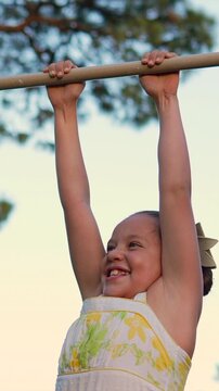 ni&ntilde;a peque&ntilde;a divertida sonriente y feliz colgada de un pasamanos en un parque infantil al aire libre disfrutando de su ni&ntilde;ez y haciendo juegos y ejercicio en su infancia 