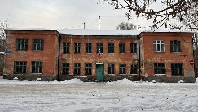 Old Weathered Orange Building Facade in Winter with Snow and Icicles