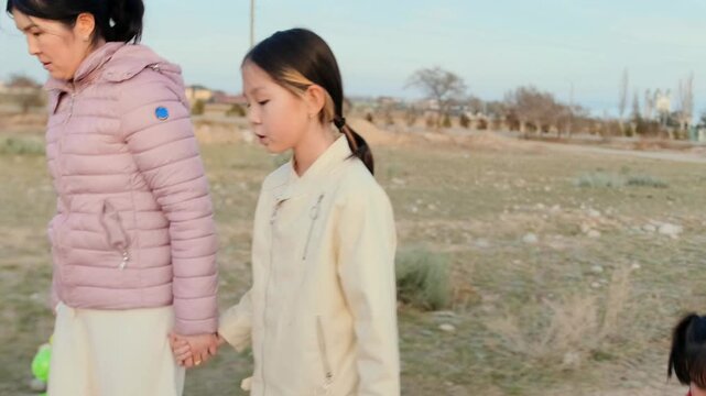 Mother walking with three daughters outdoors holding watering can. Authentic everyday lifestyle moment, natural behavior captured indoors, cinematic shot emphasizing real life emotions and daily rou