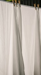 White laundry hangs drying naturally outside secured by wooden clips on a line