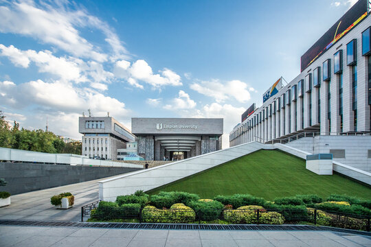Contemporary architecture of the Caspian University campus with green lawn and stairs. Almaty, Kazakhstan - October 03, 2024