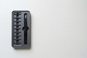 Black Tweezers and Replacement Stylus Nibs Kit in Tray on White Textured Background Top View