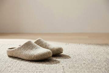 Obraz premium Beige felt slippers on woven rug in minimalist home interior