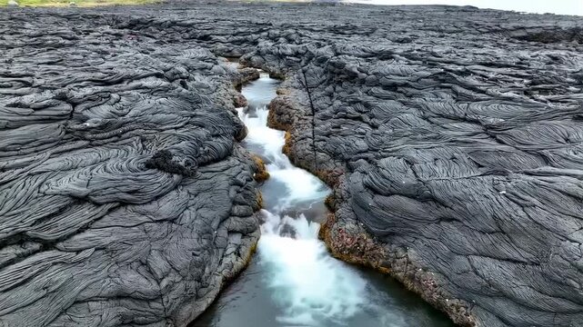 A river cuts through solidified lava flows creating a winding path