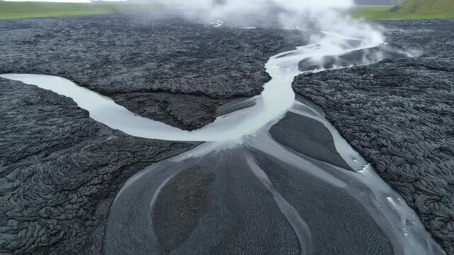 Aerial view of a river cutting through dark, textured volcanic landscape