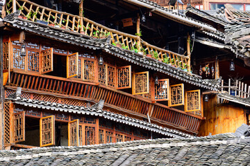 Obraz premium A traditional Miao village building in Guizhou, showcasing the distinct brownish-yellow fir timber framework and the layered gray ceramic roof tiles, embodying the rustic architectural style.