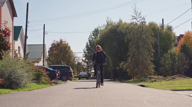 man cycling down quiet suburban street under warm autumn sunlight, passing parked cars and leafy gardens, wearing jacket and helmet, slow steady pace conveys calm weekend commute and relaxed