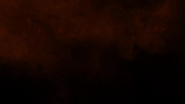 Orange smoke and fog effect moving slowly. Isolated on black background, ideal for compositing