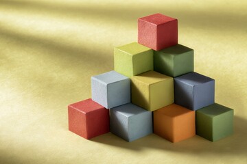 Obraz premium Colorful geometric cubes stacked in pyramid formation on yellow background