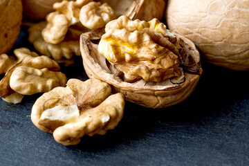 Obraz premium Macro view organic ripe walnut harvest on black stone background.