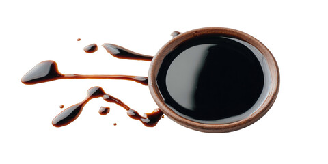 Dark liquid spills from a small, round earthenware bowl on a black background