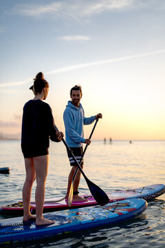 Paddle boarders moving calmly across the water at sunset, mindful outdoor moment with relaxation