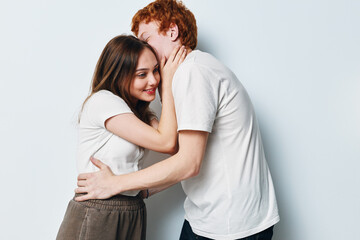 Fototapeta premium Couple embracing with affection and intimacy on white background. Young man and woman touching faces, showing love, connection, and care in casual clothes, relationship moment.
