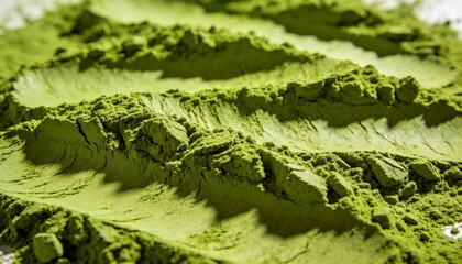 Macro shot showing the fine, velvety texture of vibrant green matcha powder. The surface is arranged in soft waves and ridges, highlighting the quality of the ground Japanese tea ingredient