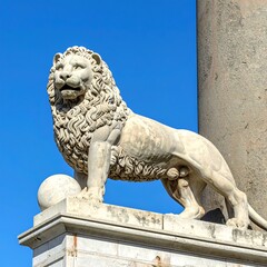 A majestic stone lion statue on a pedestal against a blue sky