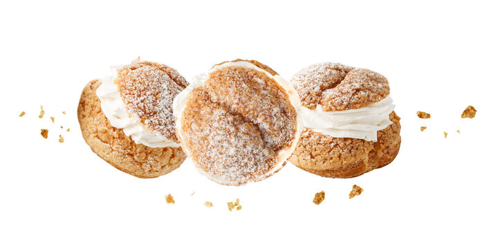 Cream puffs, pastry from choux covered sugar powder with crumbs flying isolated on white background. Sweet dessert for coffee break