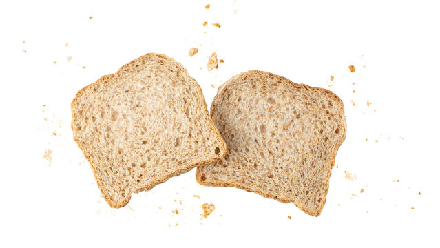 Cutting slices of wholegrain wheat bread with crumbs flying isolated on white background. Toast bread pieces.