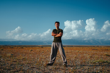 Happy young man standing with arms crossed outdoors