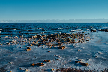 Ice on lake in the winter, distant mountains, and clear sky