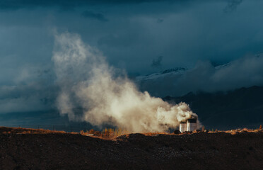 Cement plant emitting large white cloud of smoke near mountains, Kyrgyzstan