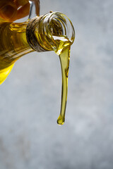 Organic olive oil pouring from carafe on vintage stone background