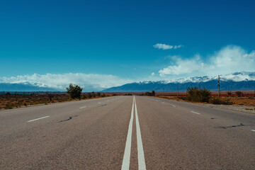 Lonely road with double solid line on sunny day with mountains