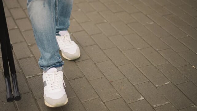 Quiet moment after performance, Stagehand walks away as sneakers pause, Worn denim and steady steps mark end of event, Closeup of footwear and gear capturing silent conclusion of show