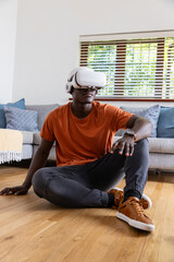 Virtual reality headset resting on hardwood floor in living room with sofa and cushions