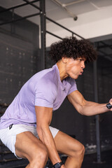African american adult male gripping cable handle performing row in gym with smartwatch