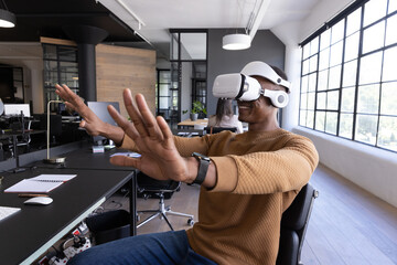 Vr headset displaying immersive interface at open-plan office desk, with notebook, potted plant