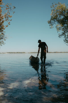 Man launching canoe in tranquil summer lake, oregon