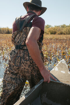 Hunter standing in waders next to hunting canoe