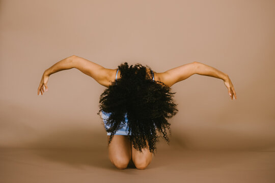 Black female dancer bent over making shape and pose with arms