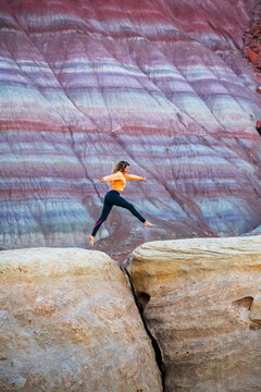 Athletic female jumping a gap in Utah striped hills
