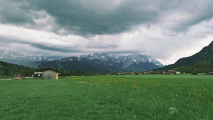 Obraz premium Countryside village below high snowy mountains