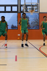 Obraz premium Male basketball teammates practicing drills near glass backboard and basketballs in court